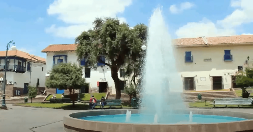 entro de la ciudad de Cusco con una pileta en el centro y personas sentadas en los bancos, uno de los mejores lugares gratis para visitar en Cusco